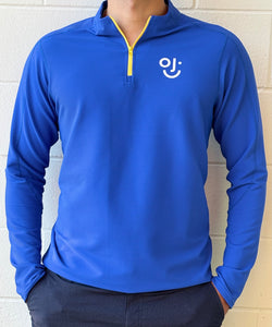 Blue long-sleeve quarter zip with OJI logo on a white brick wall background
