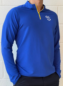 Blue quarter-zip with OJI logo against a white brick wall.